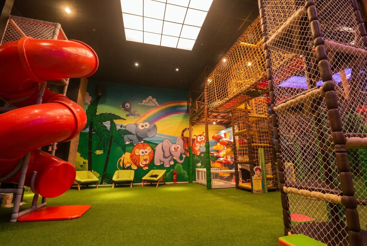 Espaço kids do Coco Bambu com escorregador vermelho, mural de animais e área de brincadeiras